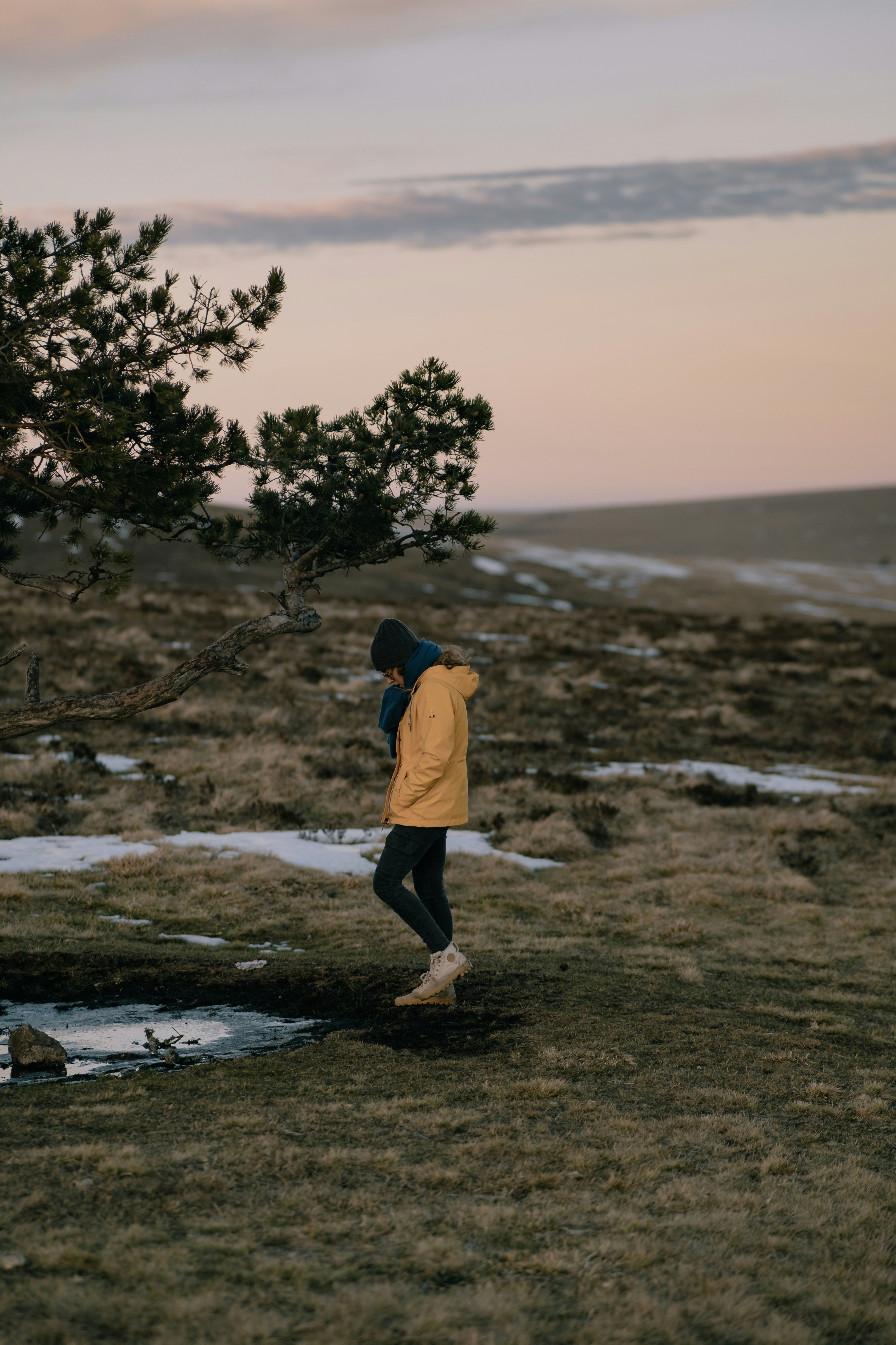 person in yellow hoodie standing on seashore during daytime